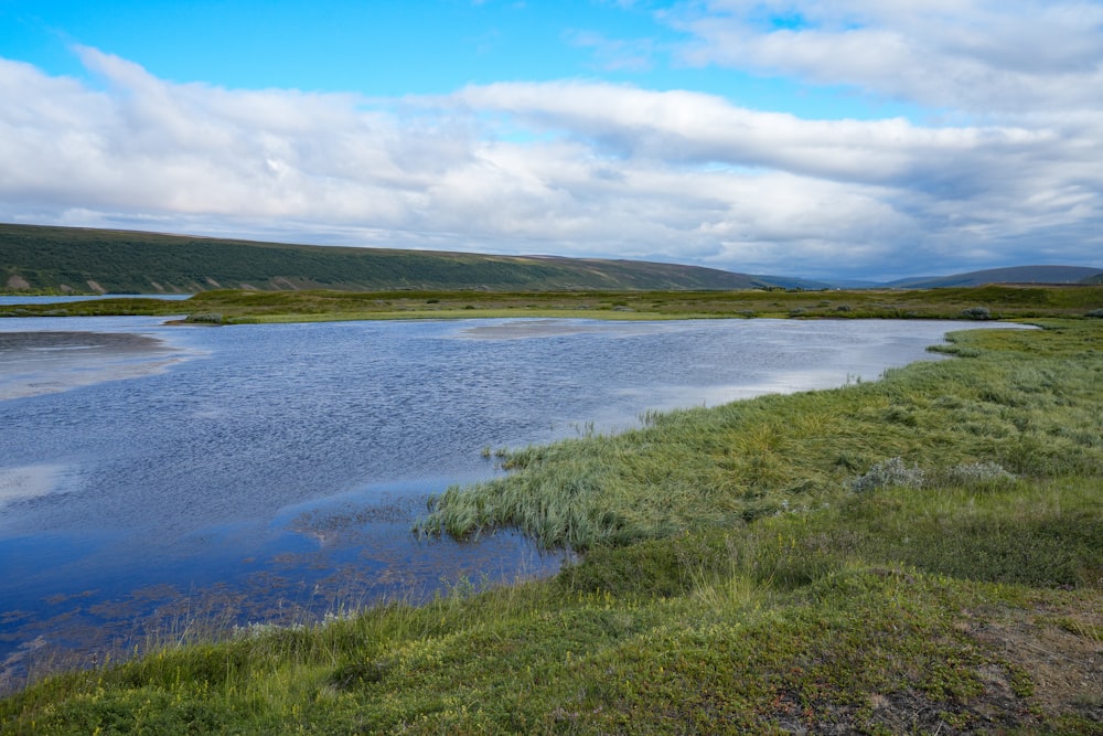 a large body of water surrounded by a lush green field