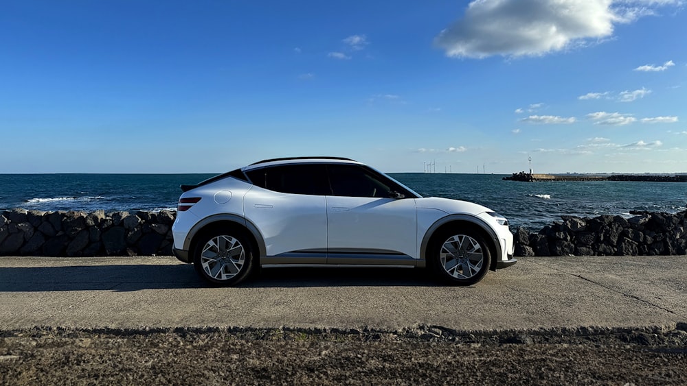 a white car parked on the side of a road next to the ocean