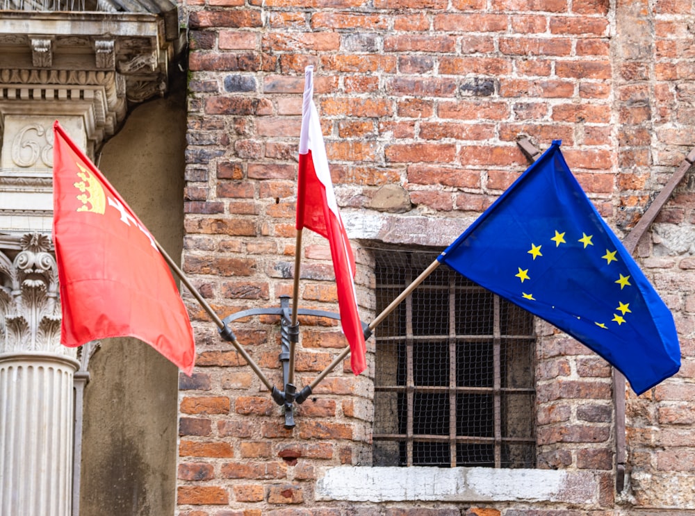 two flags are flying in front of a brick building