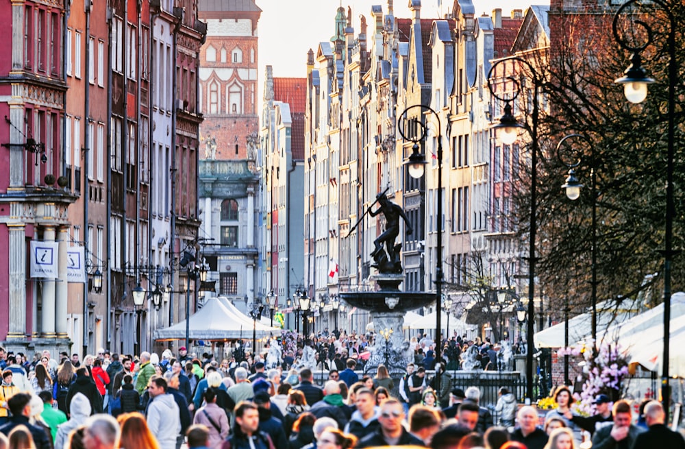 a crowd of people walking down a street next to tall buildings