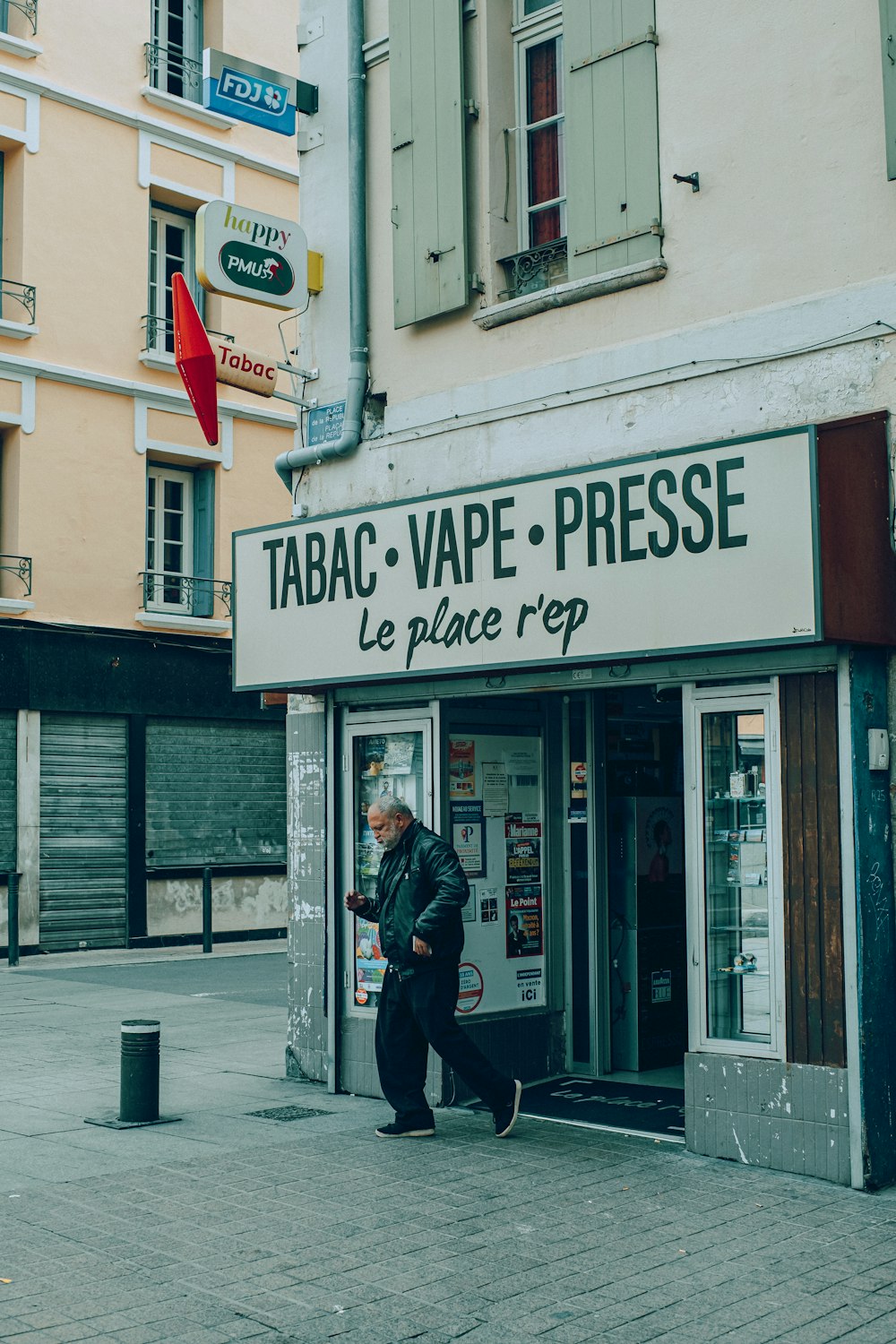 a man walking past a restaurant called tabac vape - presse