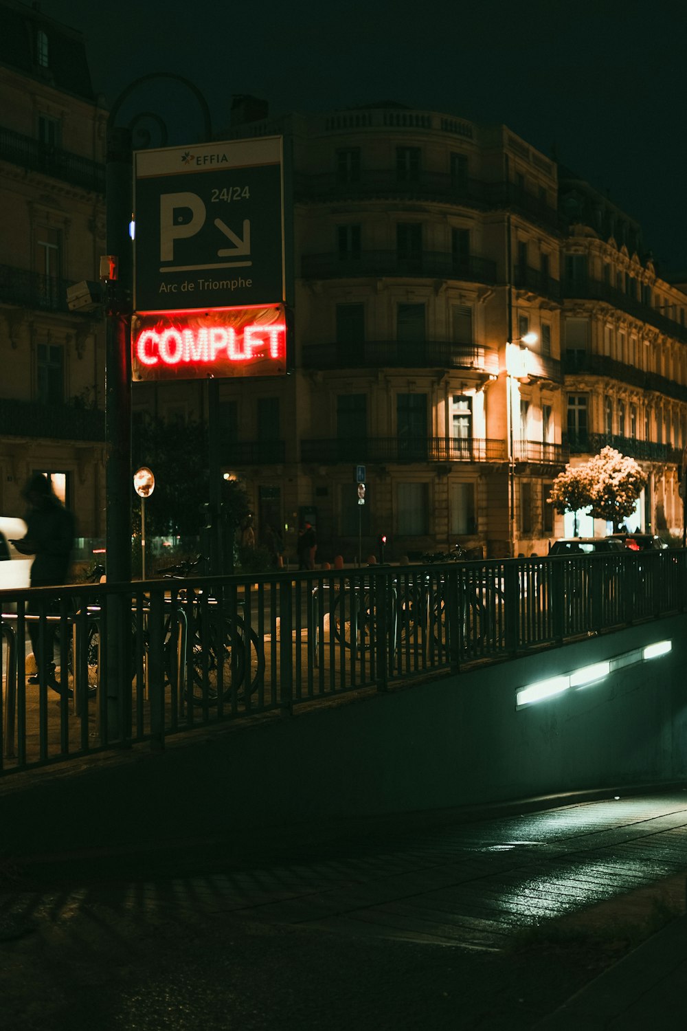 a couple of people walking across a bridge at night