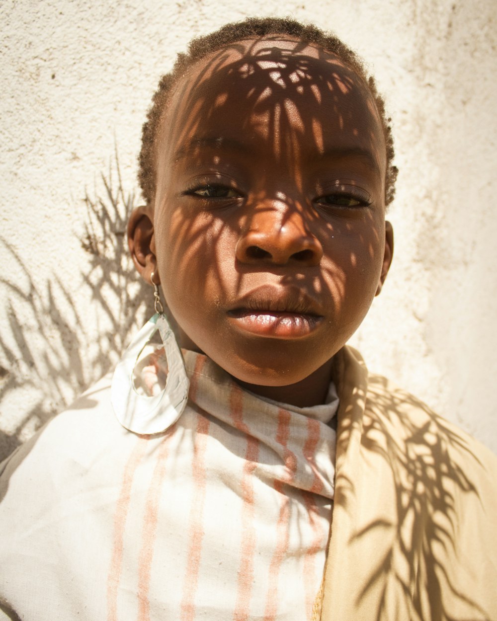 a young child with a shadow of a tree on his face