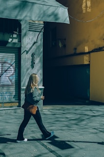 a woman walking down a street past a building