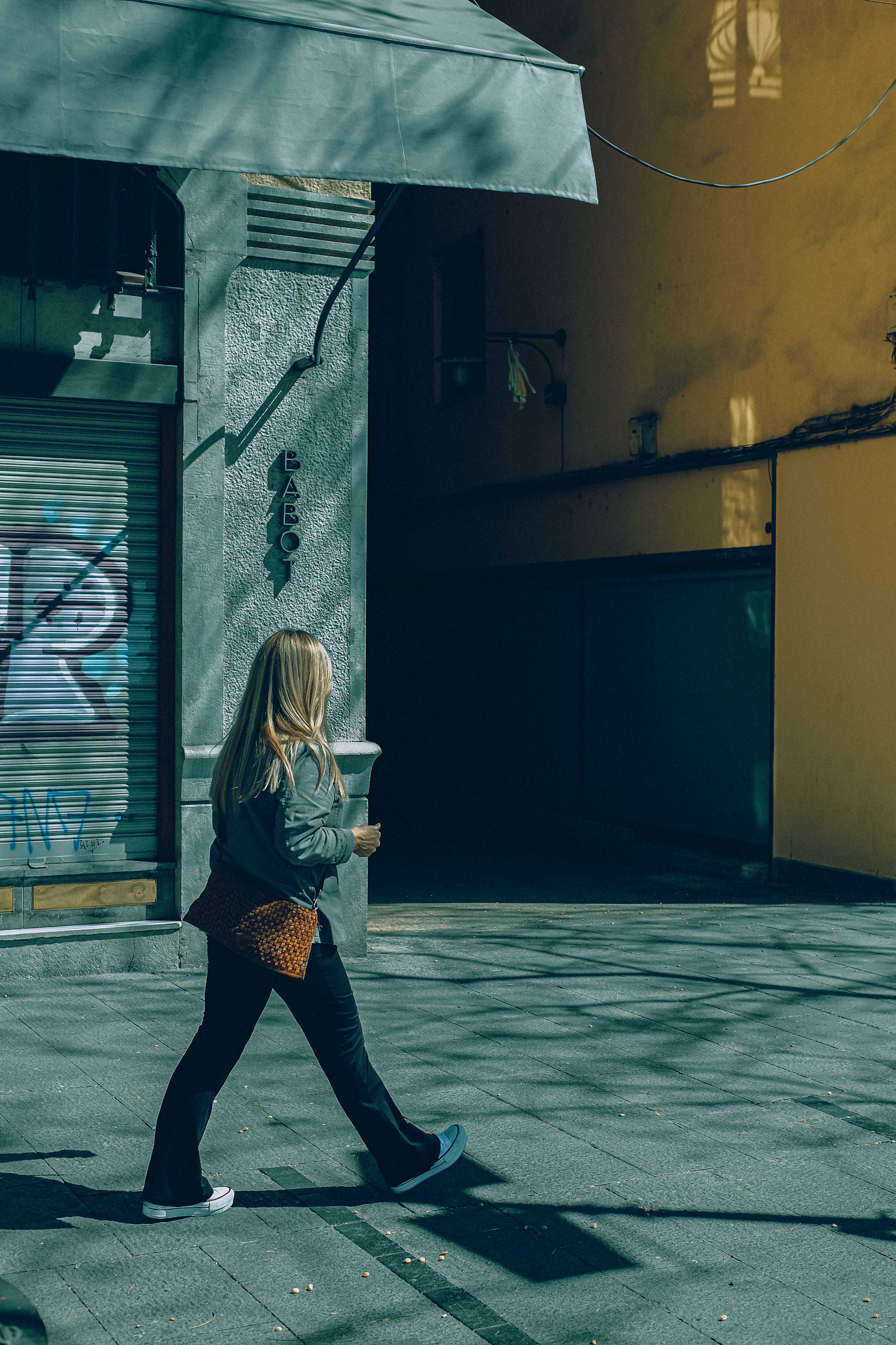 a woman walking down a street past a building