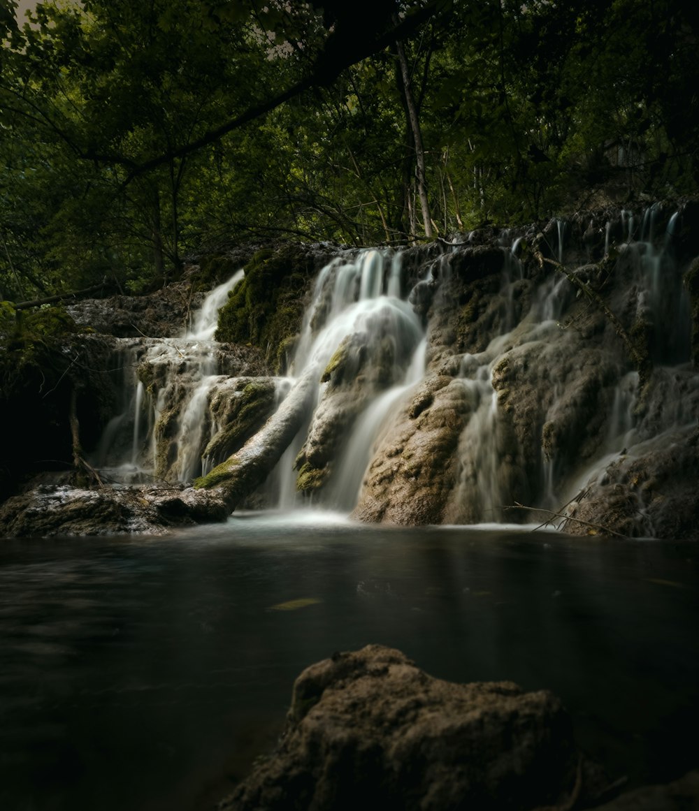 a small waterfall in the middle of a forest