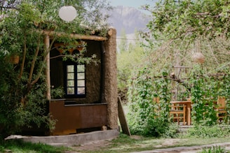 a small building with a window in the middle of a forest