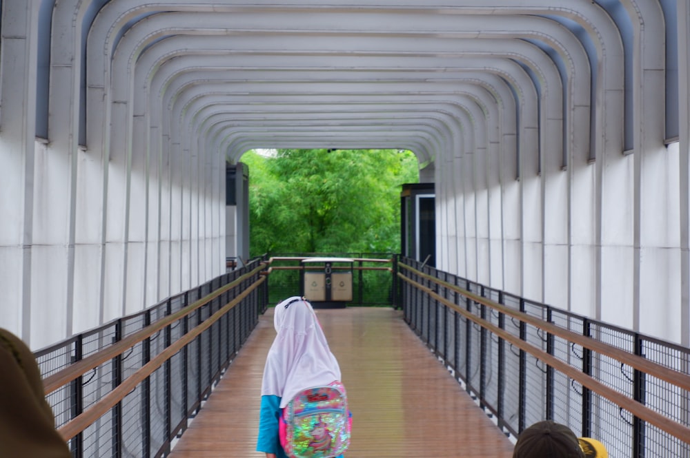 a child is walking down a bridge with a backpack