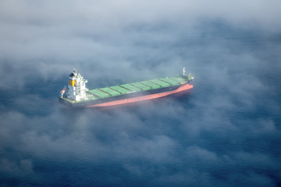 Barco de carga navegando sobre un mar de niebla