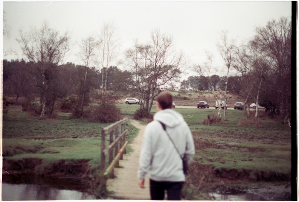 a man walking across a bridge over a river