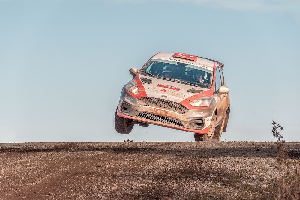 Une voiture de rallye sautant par-dessus un chemin de terre