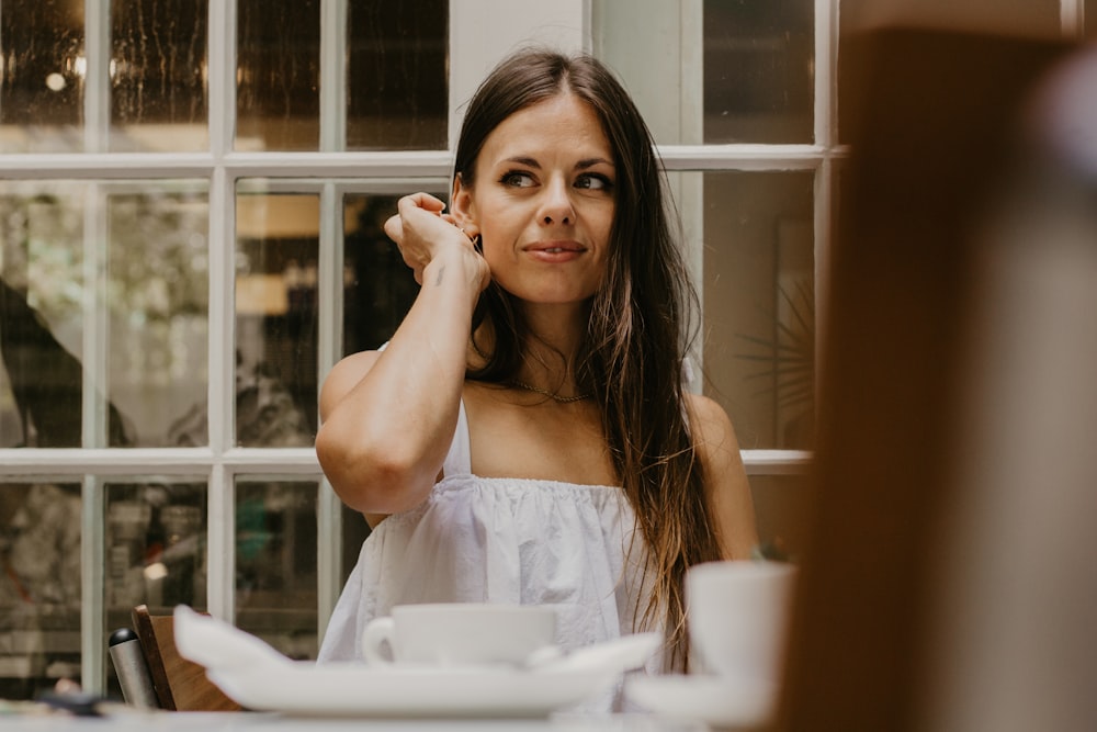 a woman sitting at a table in front of a window