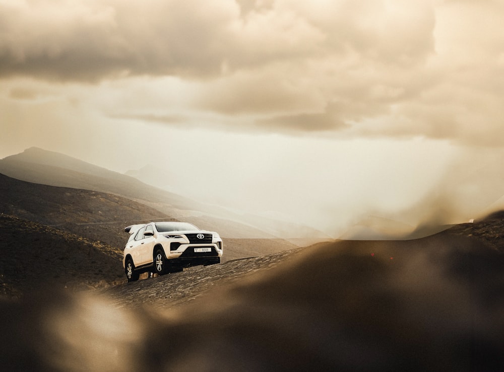 a white suv driving down a dirt road