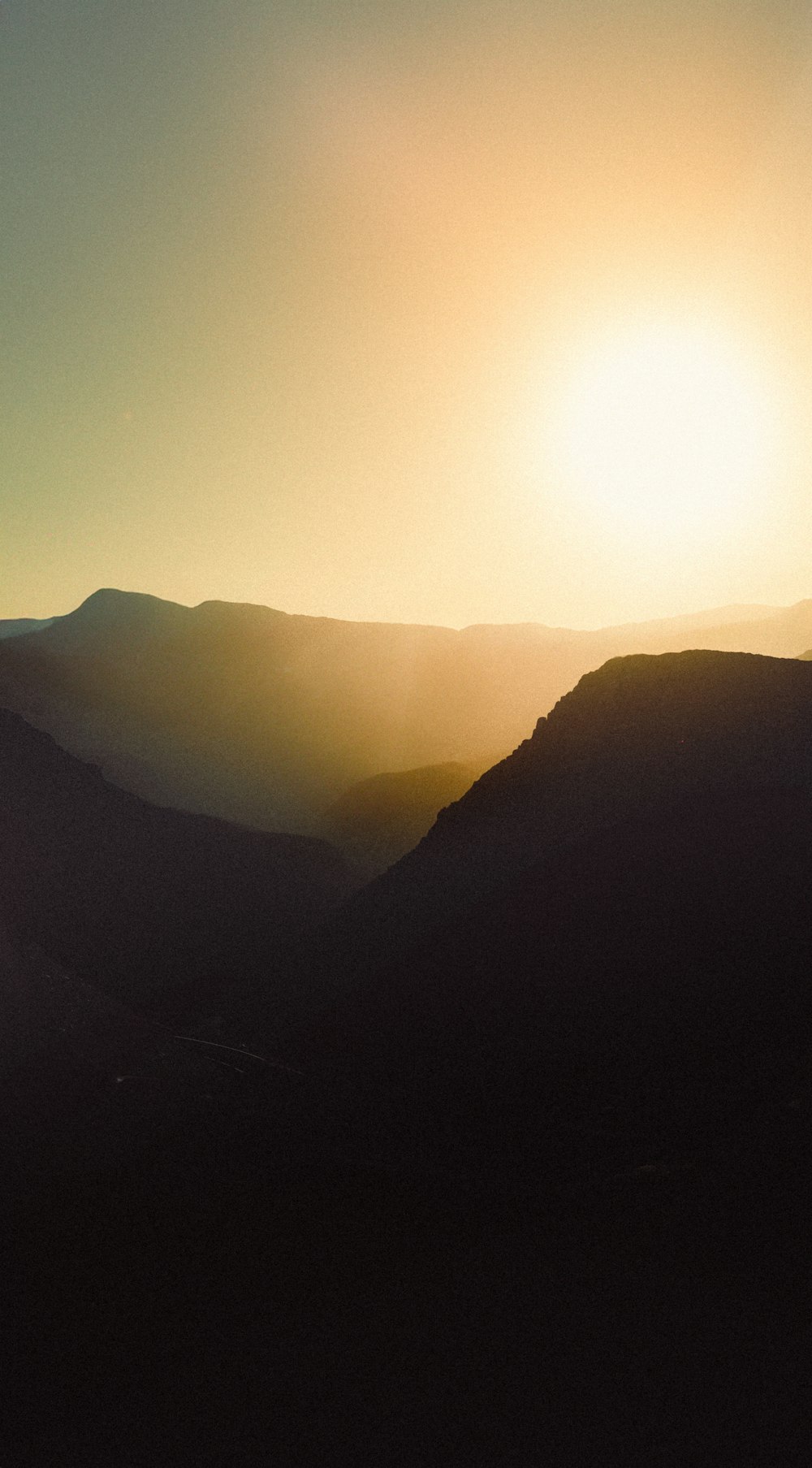 the sun is setting over a mountain range