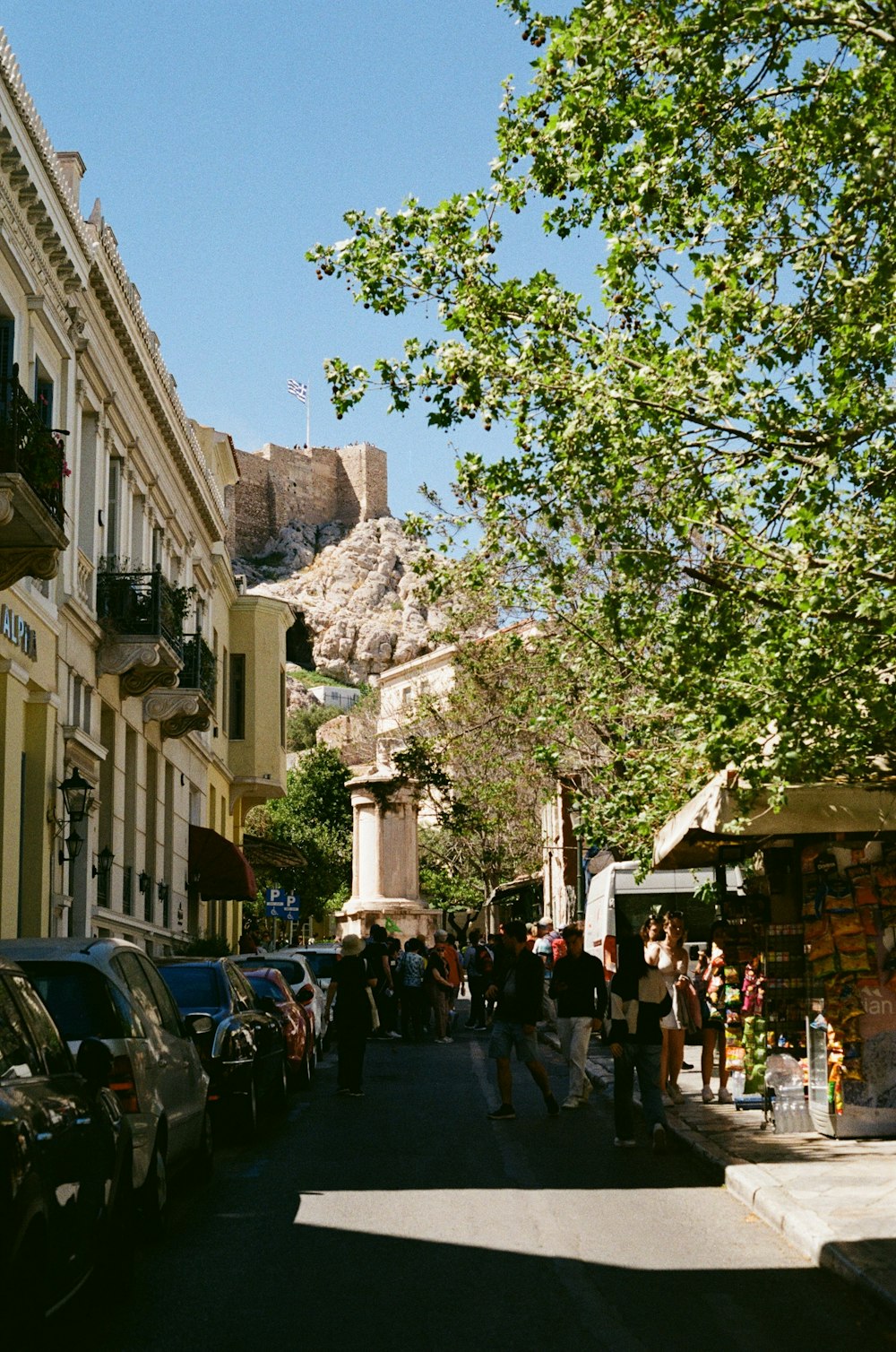 a group of people walking down a street next to tall buildings