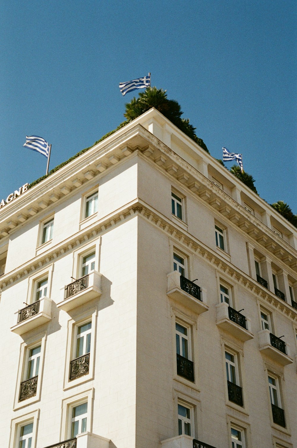 a tall white building with flags on top of it