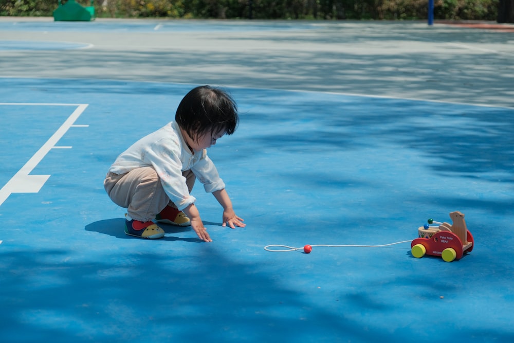 a young child playing with a toy car on a tennis court