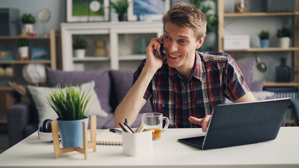 a man sitting at a table talking on a cell phone