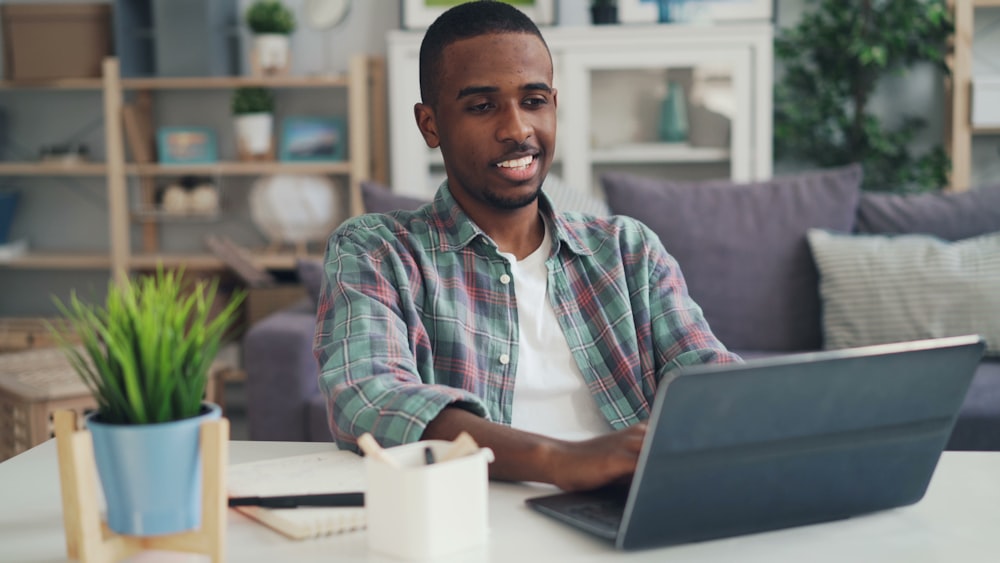 a man sitting at a table using a laptop computer