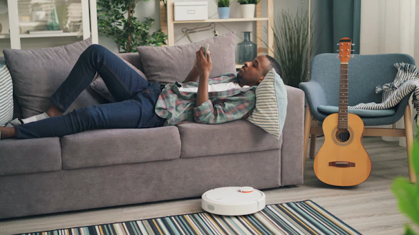 a man laying on a couch next to a guitar