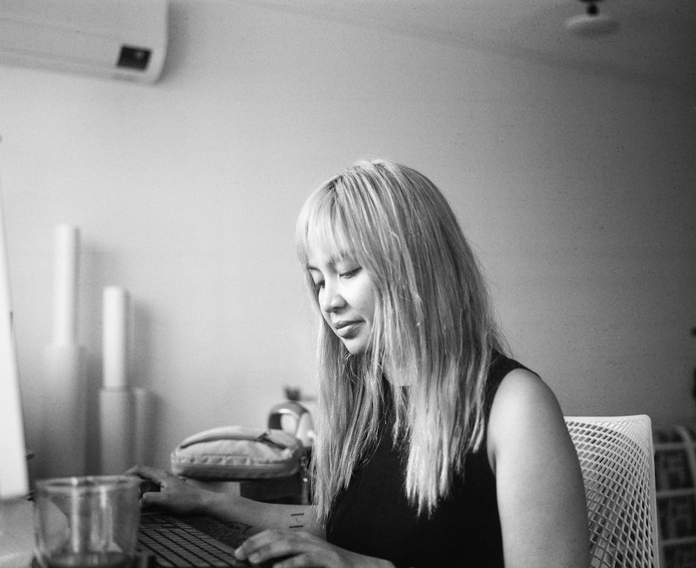 a black and white photo of a woman typing on a computer
