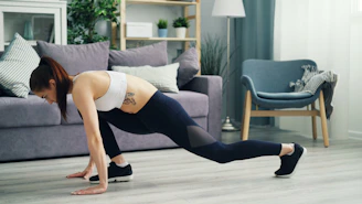 a woman is doing a push up in a living room