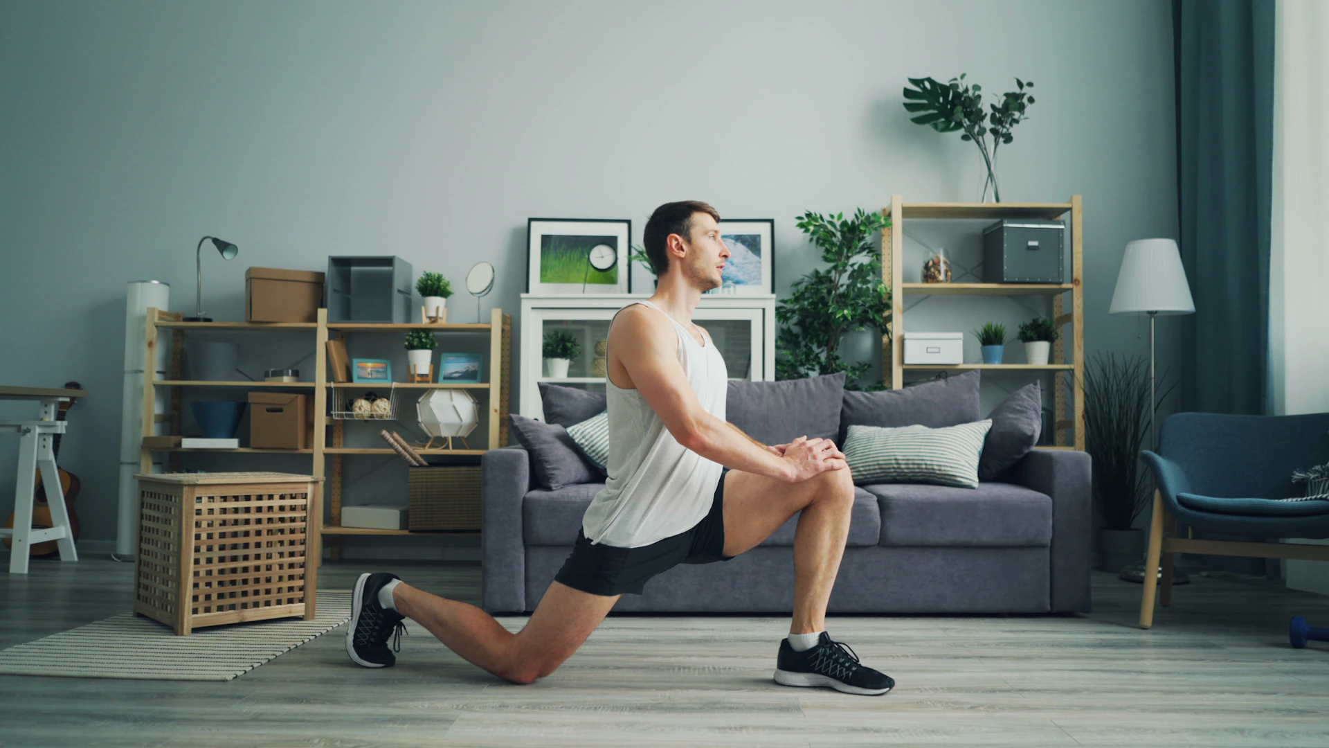 a man in a white tank top is doing a squat exercise