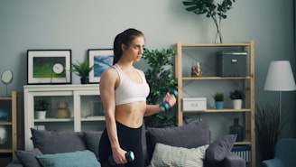 a woman in a sports bra top is holding a dumb