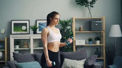 a woman in a sports bra top is holding a dumb