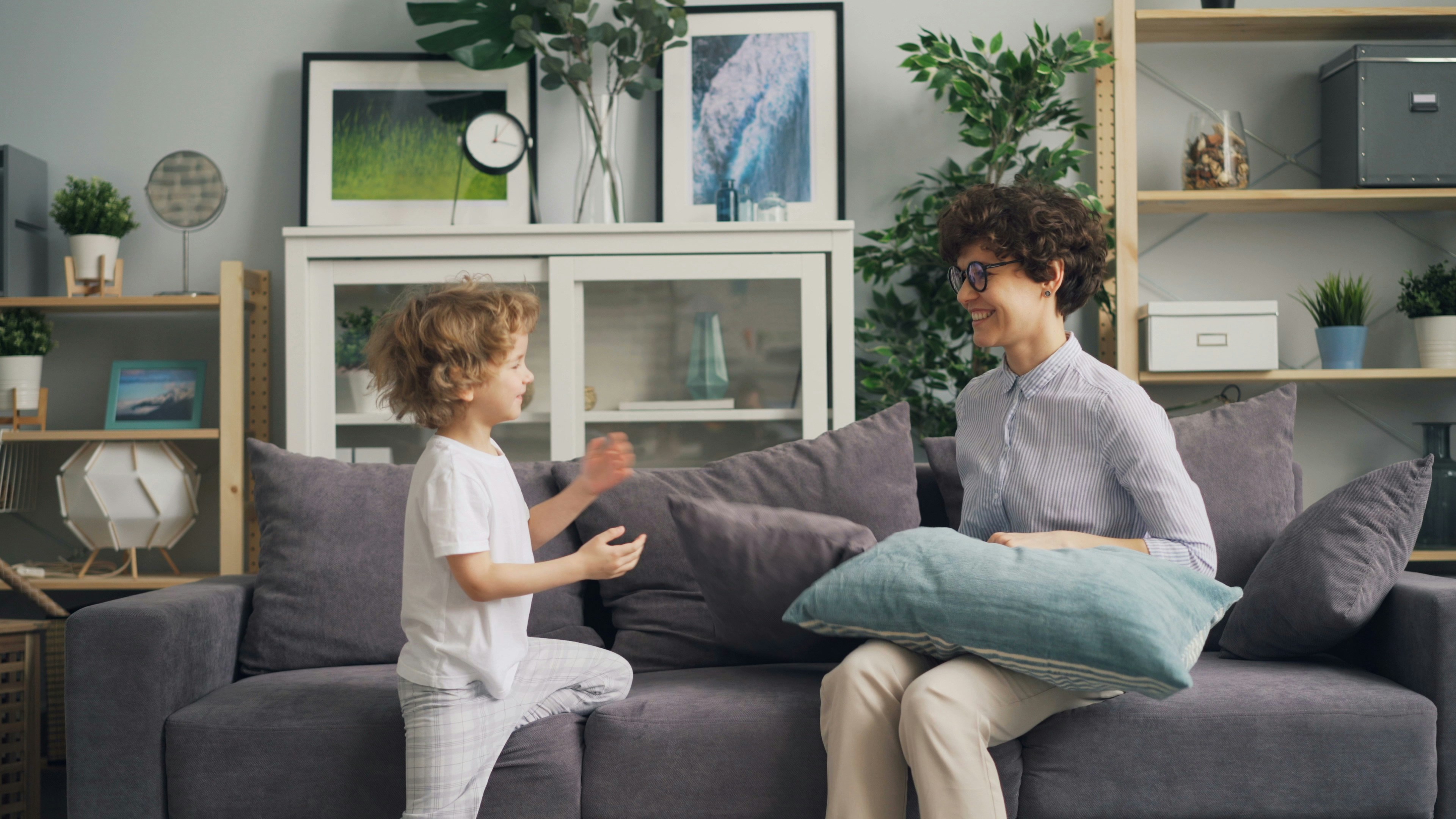 a woman sitting on top of a couch next to a little boy