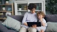 a woman and a child sitting on a couch looking at a laptop