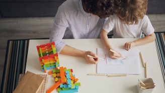 a woman and a child sitting at a table working on a project