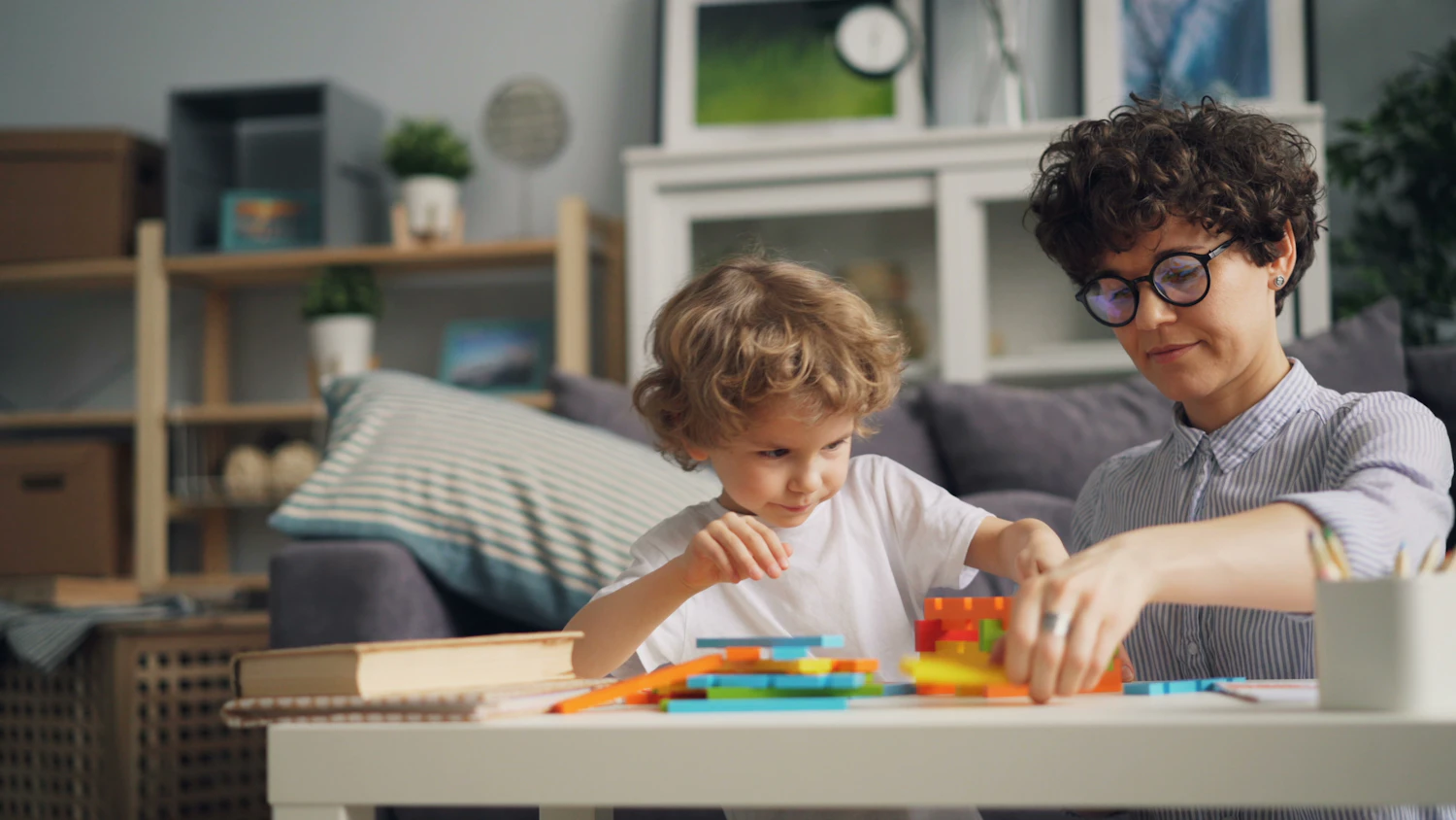 A parent practicing show and tell with a child at a table