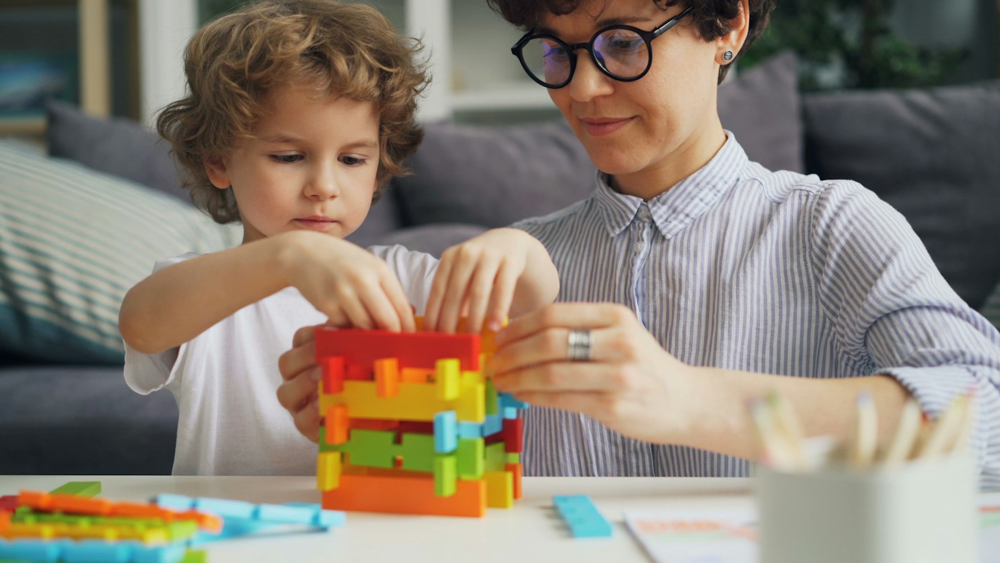 A parent and child building with blocks together — the kind of back-and-forth screens at their worst displace.