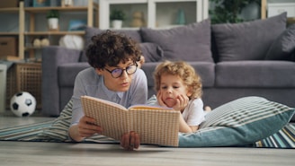 a man and a little girl laying on the floor reading a book