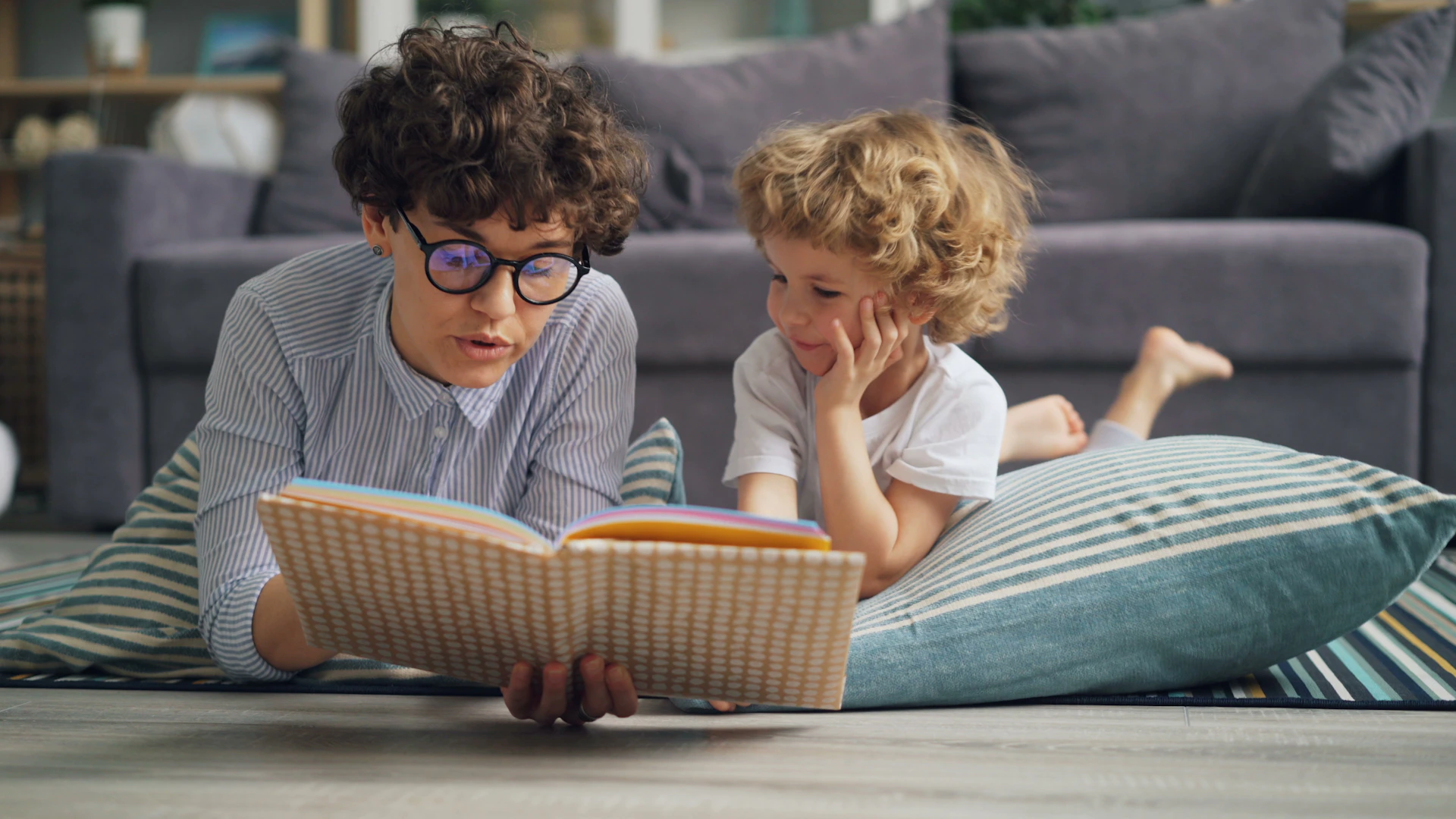 a man and a little girl laying on the floor reading a book