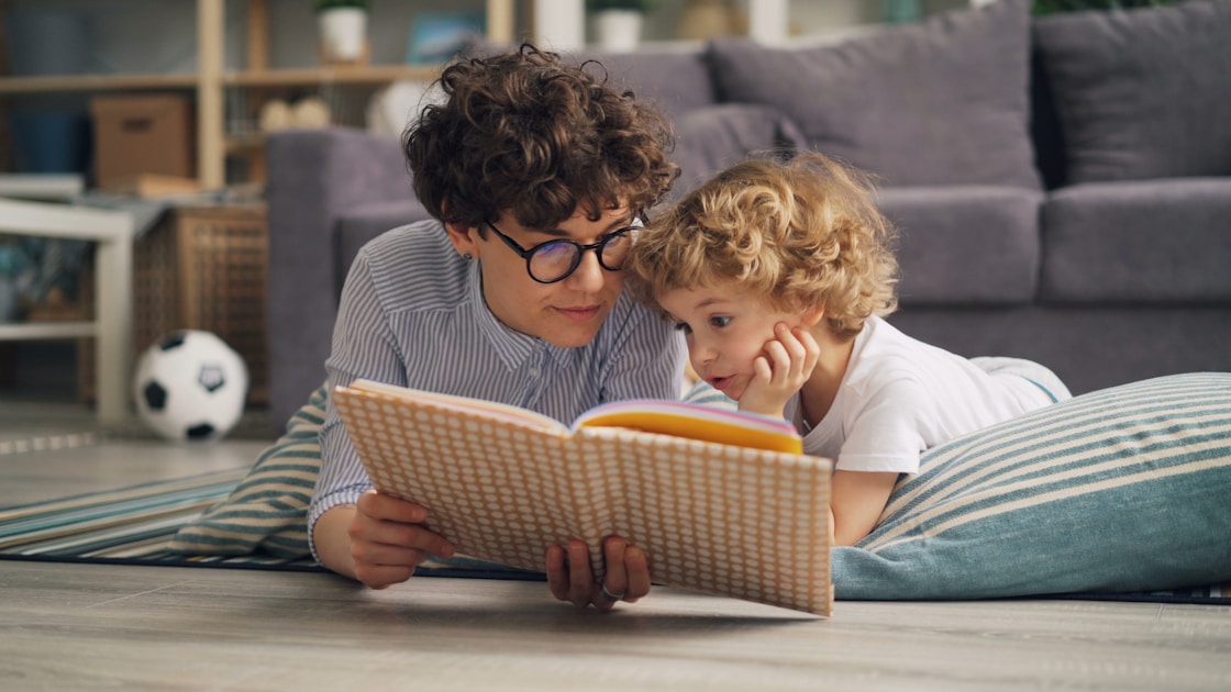 Adult and child reading together on floor - explaining neurodivergence to siblings