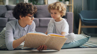 a woman reading a book to a child on the floor