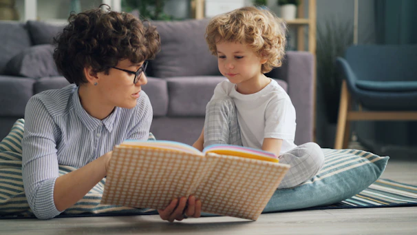 a woman reading a book to a child on the floor
