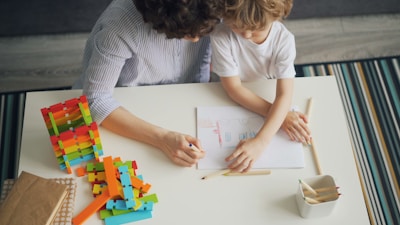 a woman and a child sitting at a table working on a project