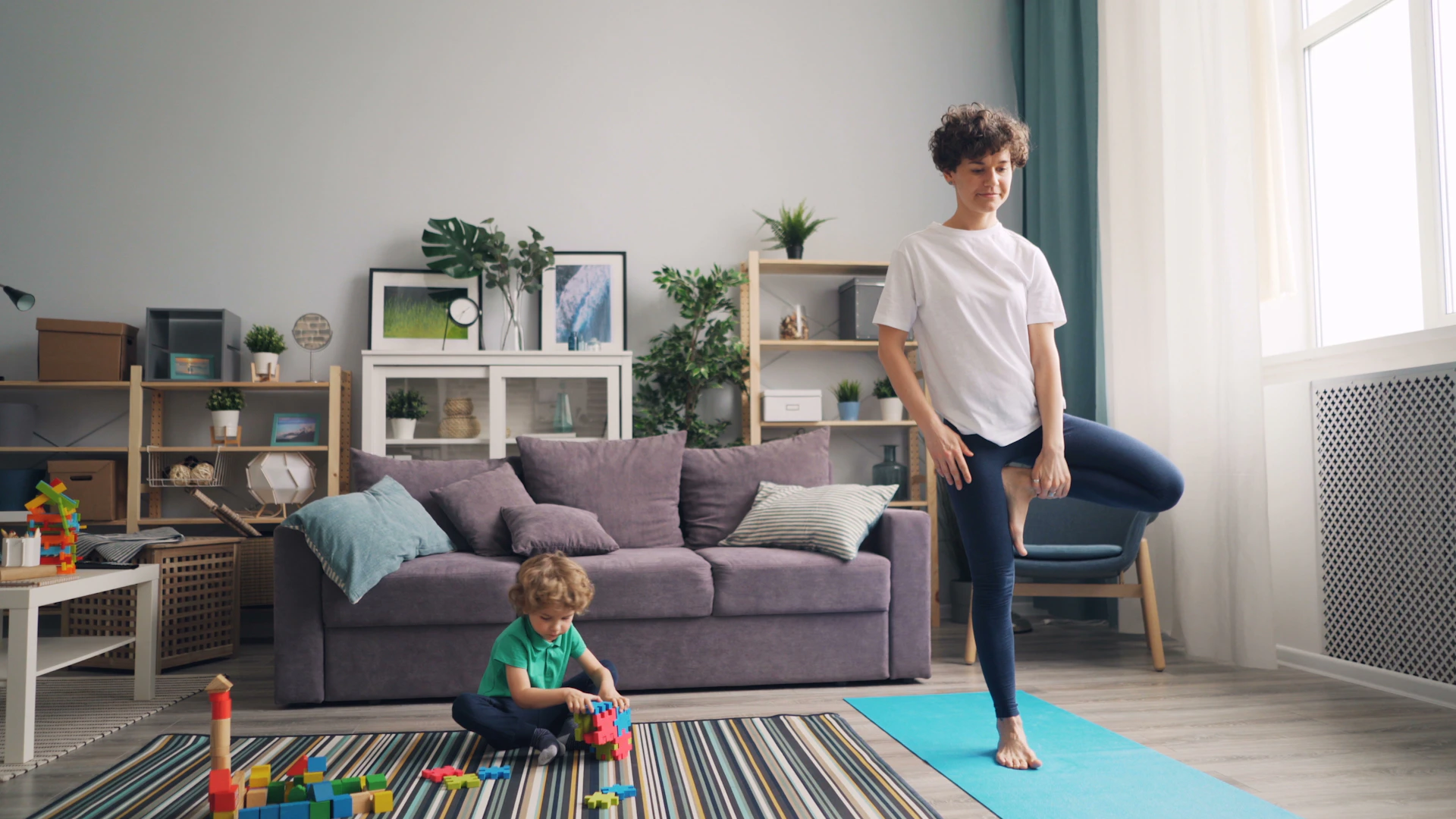 a woman standing in a living room next to a child