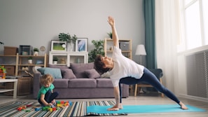 a woman and a child doing yoga in a living room