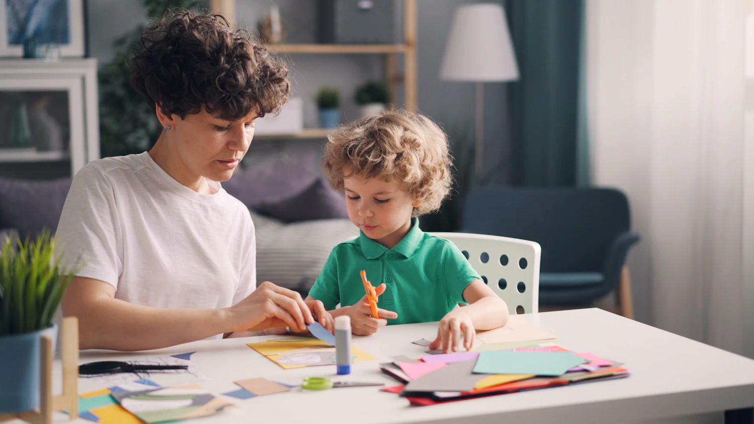 A grown-up helping a young child at a craft table