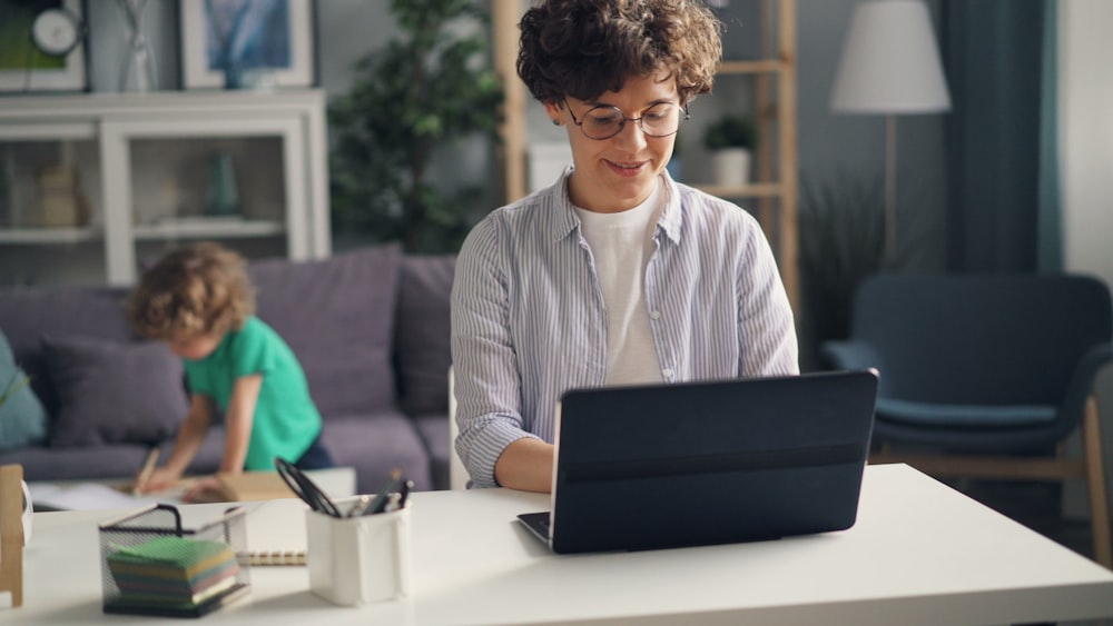 a woman sitting at a table using a laptop computer