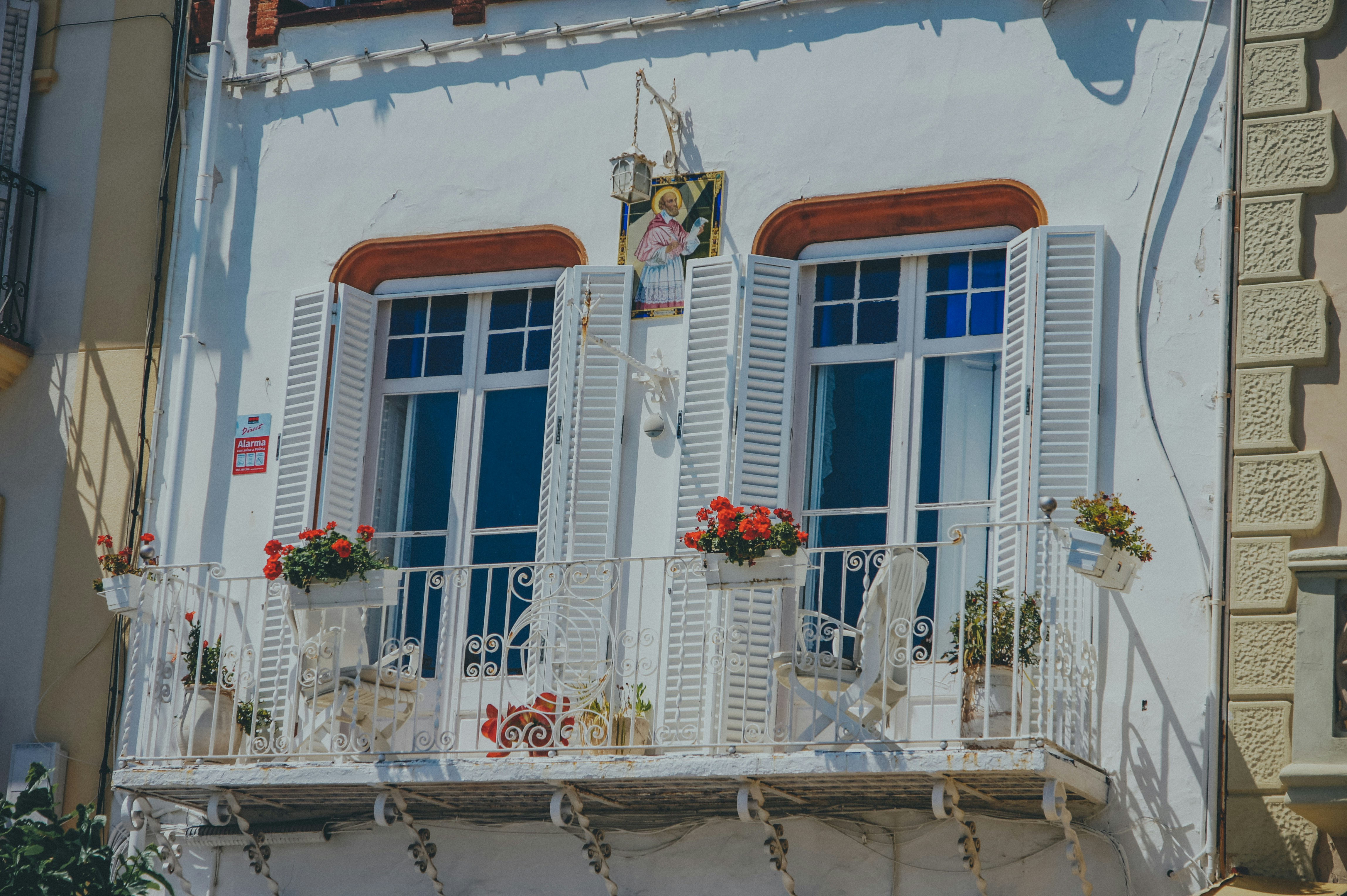 a balcony with white shutters and flowers on it
