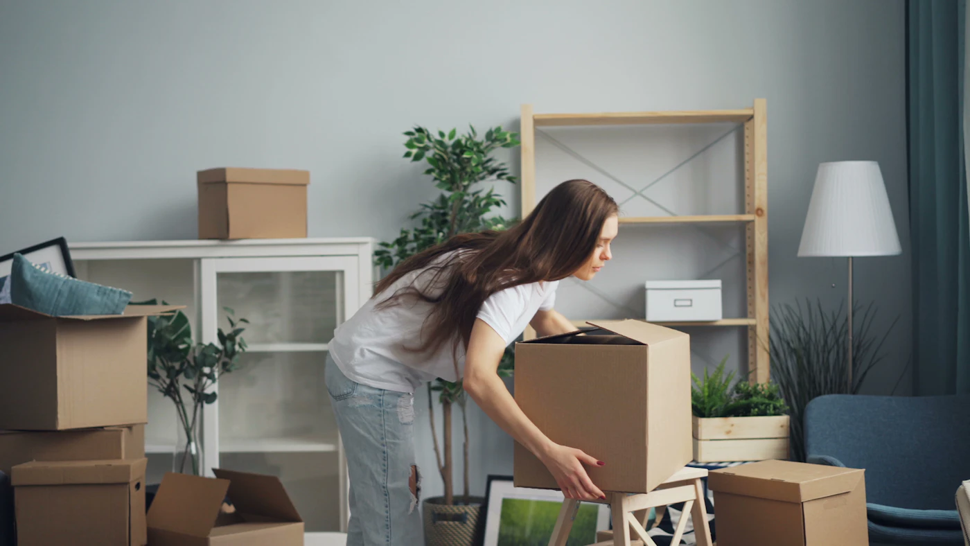 A woman calmly moving boxes in a living room