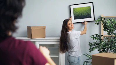 a woman hanging a picture on a wall