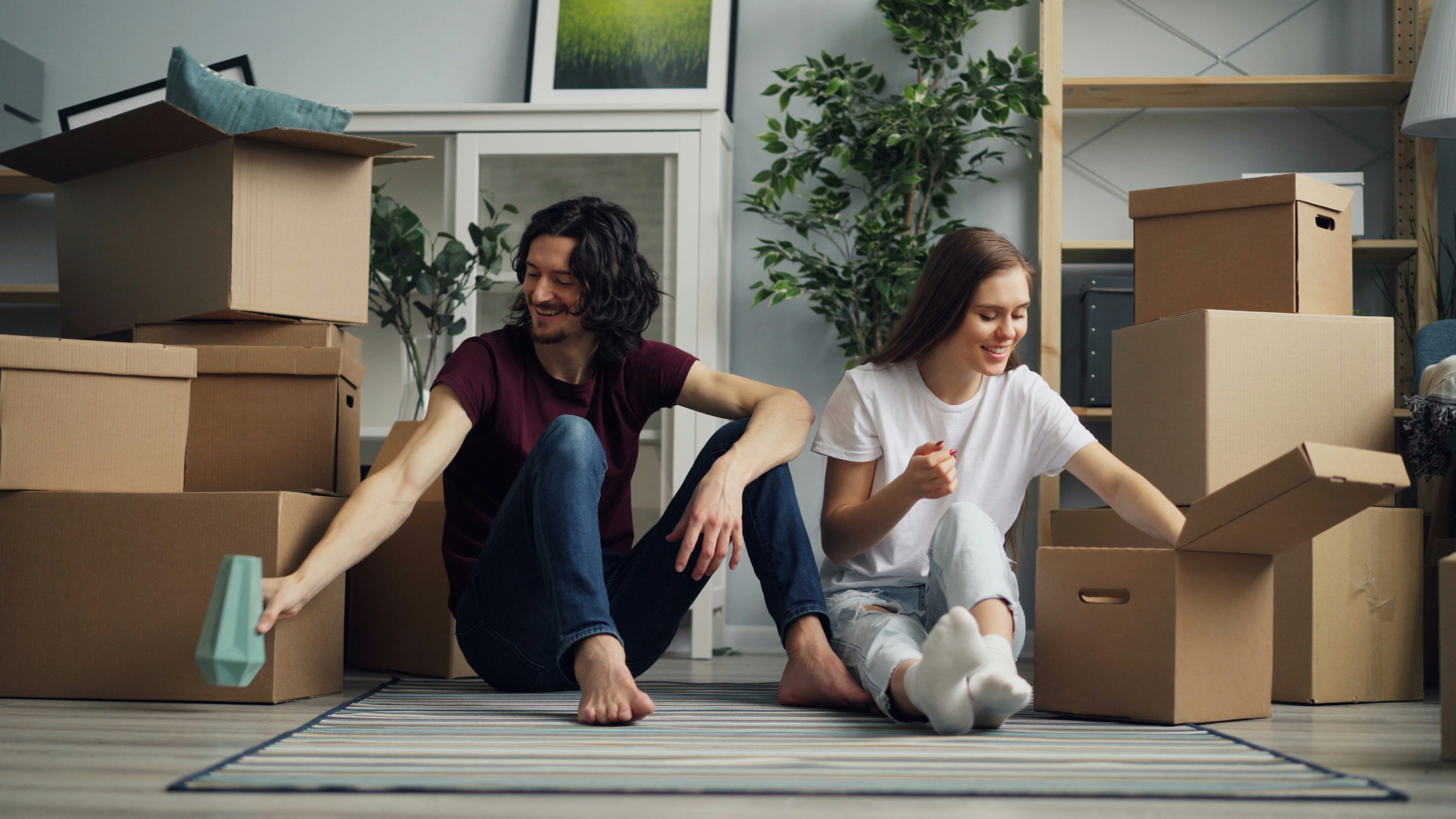 a man and a woman sitting on the floor surrounded by boxes