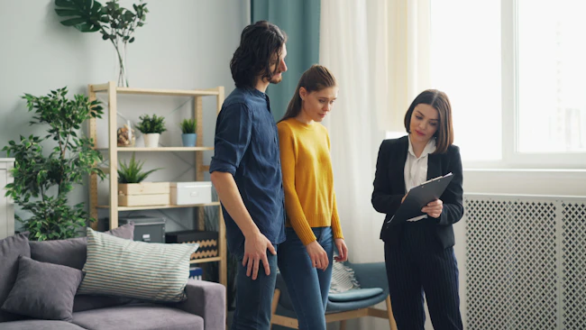 A real estate agent talking with two home buyers in a living room