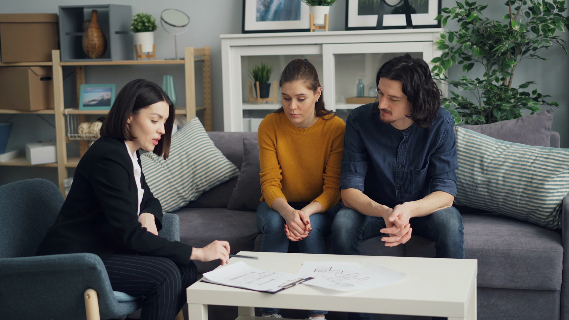 three people sitting on a couch in a living room